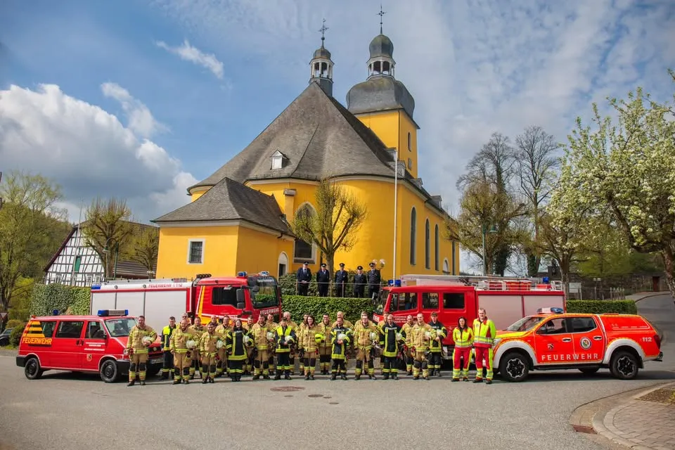 Mannschaftsfoto der Feuerwehr Friesenhagen mit allen Fahrzeugen vor der Kirche